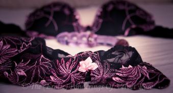 Black and pink bra discarded on bed
