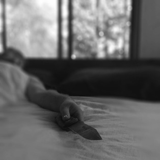 man lying in bed holding a knife
