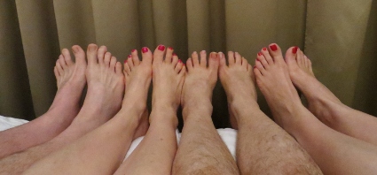 Row of four feet lined up in bed