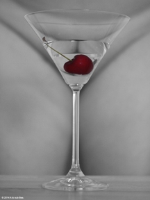 Martini glass with red cherry in front of naked woman