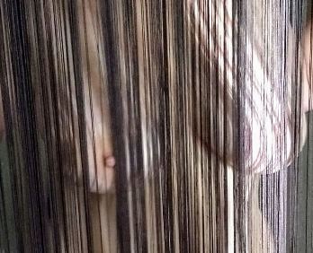 Looking through string curtain to nude woman