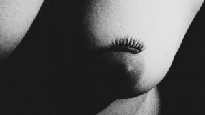 Fake eye lashes on womans breast in black and white