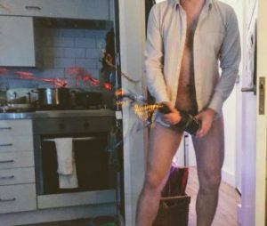 Man with no trousers on holding champagne bottle in front of his cock with streamers exploding out of it 