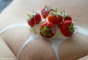 Woman with strwberries and cream on top of her shaved pubic mound