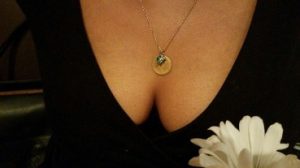 Womans cleavage with pendant and black dress and white flower in the foreground