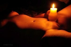 Nude of woman laying in her back holding a candle