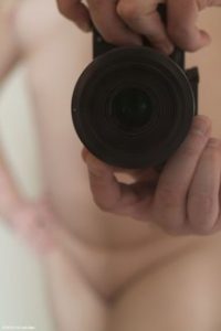 Close up of camera with photographers hands in the back ground an out of focus nude