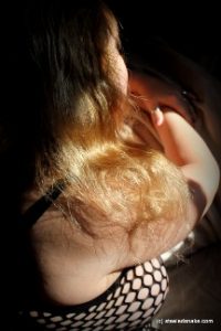 Sunlight on womans golden hair and fishnet clad breast