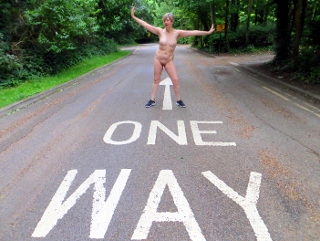 Naked woman standing over one way sign on the street