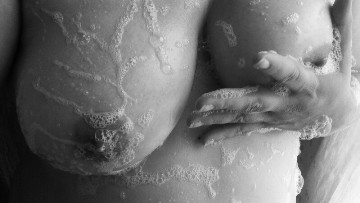 topless woman rubbing soap suds into her breasts