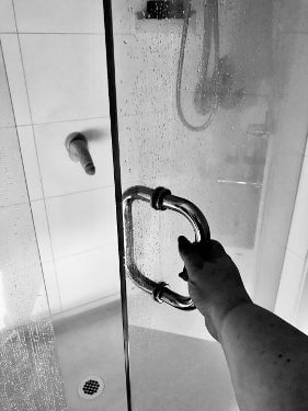 Womans hand on shower door with suction cup dildo stuck on the shower wall