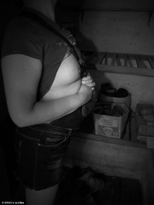 Woman in dungarees inside garden shed showing her breasts