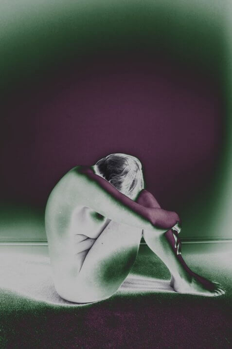 Woman sitting hugging her knees with infrared edit
