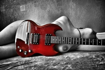 Nude woman laying behind guitar