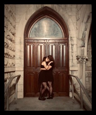 Two women kissing in the doorway of a church