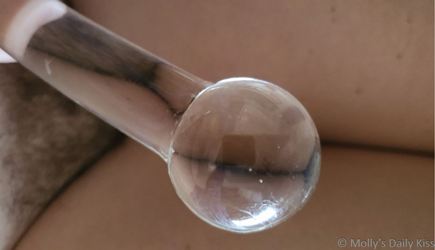 bulbous head of glass dildo with pubes reflected on the stem