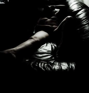 woman laying in the darkness naked on sofa