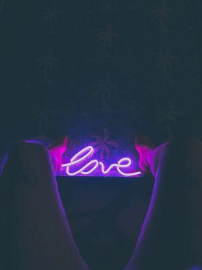 neon love sign between naked thighs