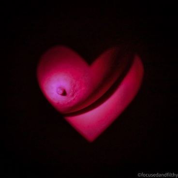 Looking through heartshaped hole to bright pink breast