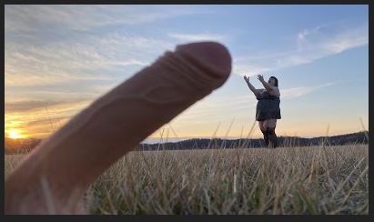 woman in field with giant penis reaching over her head