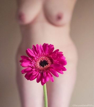 Bright pink flower with nuve body in soft focus behind it