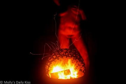 Molly standing naked in front of outdoor fire