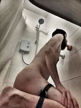 naked man kneeling in shower sucking dildo attached to the wall