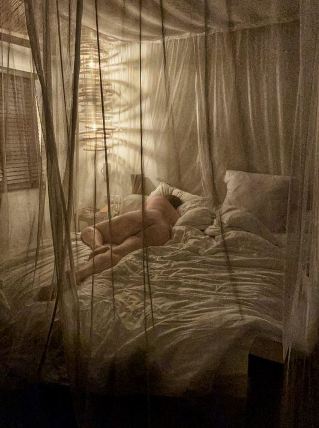Woman laying naked under mosquito net