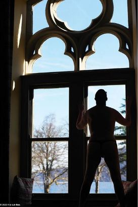 Person in thong in front of large chapel like window