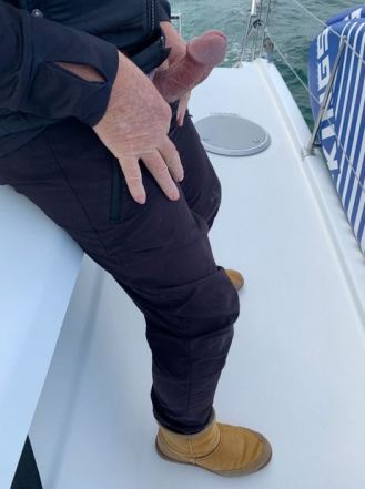 Man on boat with erect penis showing out of his trousers