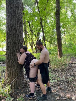 Ash leaning up against a tree with her partner fucking her from behind