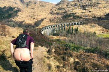 Person flashing their bum with train viaduct across the valley in the distance 