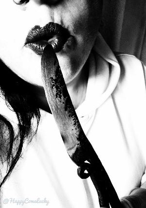 black and white of honeys lips kissing the tip of a sharp knife
