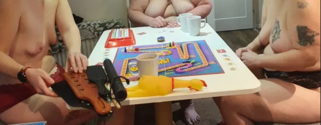3 topless people with breasts out playing a board game
