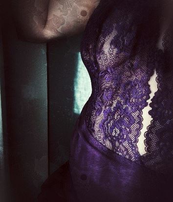 Woman in purple lingerie with sunlight on the curve of her waist