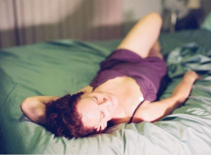 Jade laying in sunshine on bed wearing purple negligee 