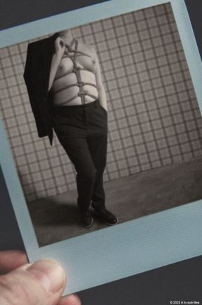 Polaroid image of Bee topless in rope harness wearing suit trousers and jacket hooked over their shoulder 