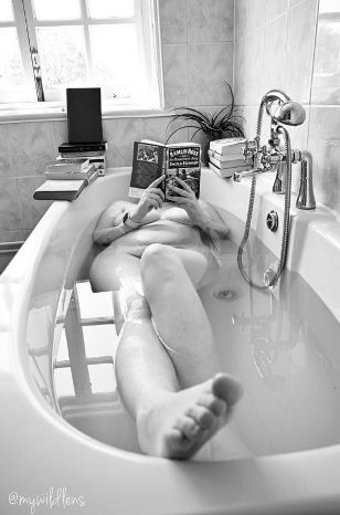 Black and white of women in the bathtub reading
