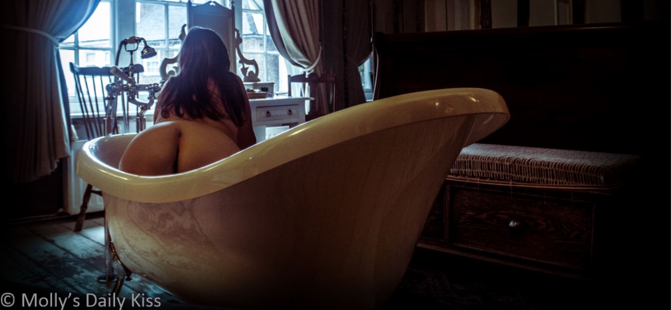 Molly kneeling in large claw foot bath tub in beautiful hotel room