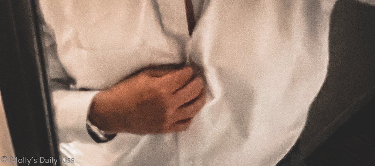 Man's hand undoing button on his white dress shirt for post called waiting for you