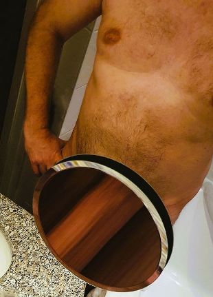 Looking down at nude man standing. Where is groin is there is small round mirror that is reflecting his arm so it looks like a giant penis for weekly round-up 719